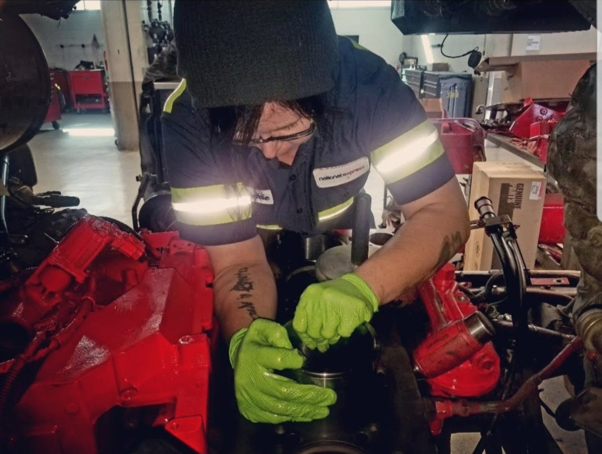 Jackie of Mechanic Mamma working on a diesel engine