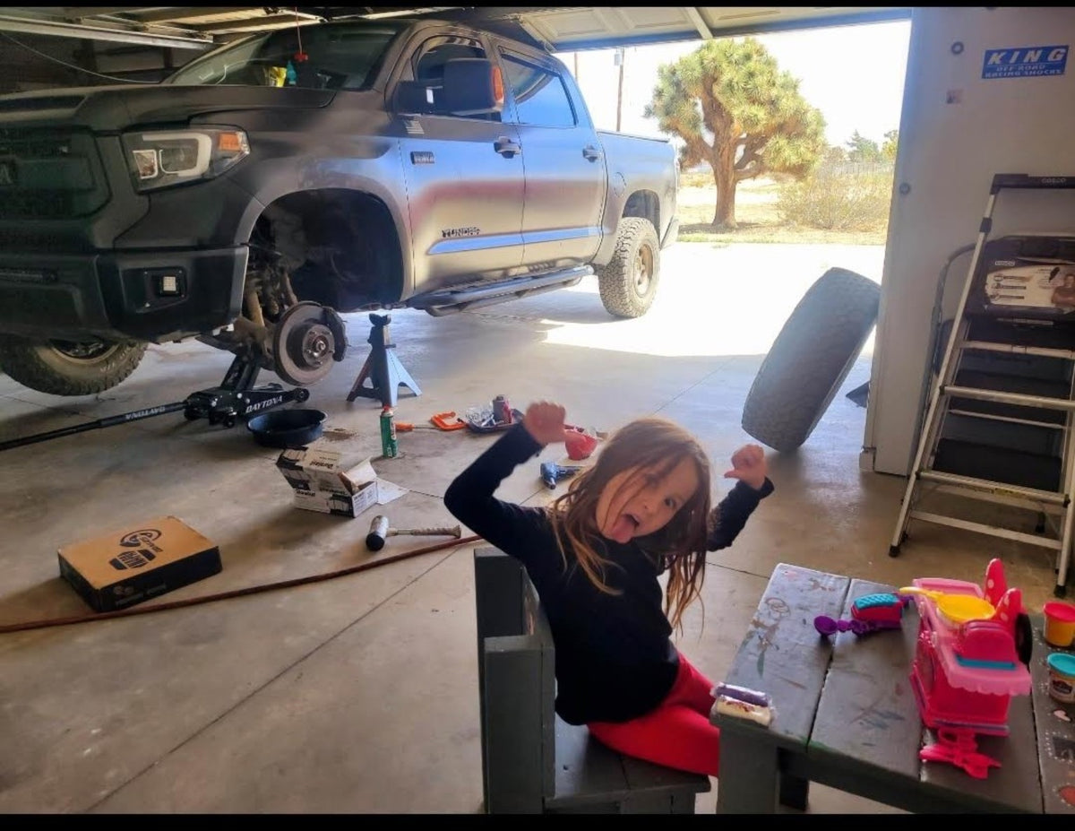 Young girl in a home garage beside a truck being worked on